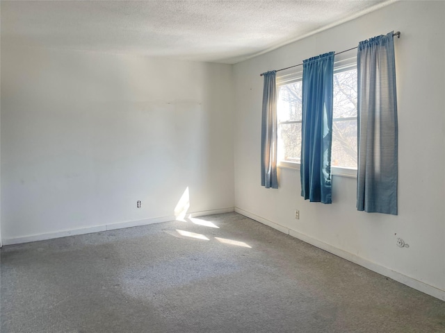 carpeted spare room with a textured ceiling and baseboards