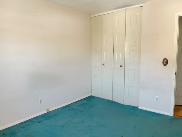 unfurnished bedroom with a closet, baseboards, and carpet flooring