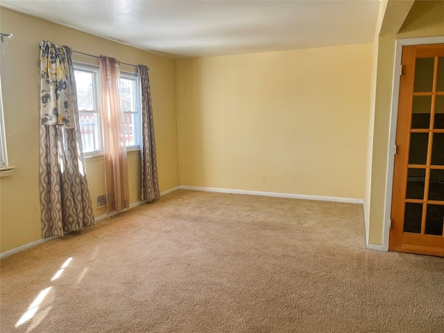 spare room featuring carpet, visible vents, and baseboards