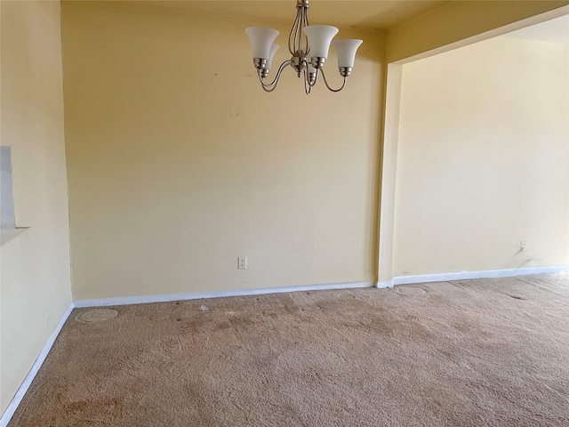 carpeted spare room featuring baseboards and a chandelier