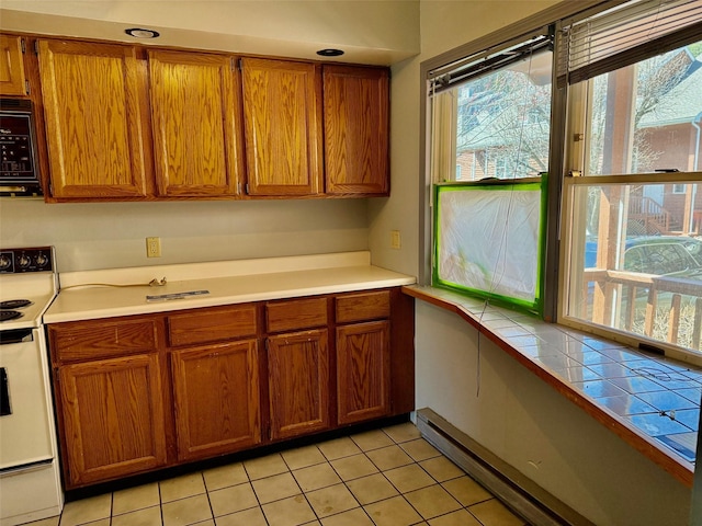 kitchen featuring black microwave, light countertops, brown cabinetry, and white electric range