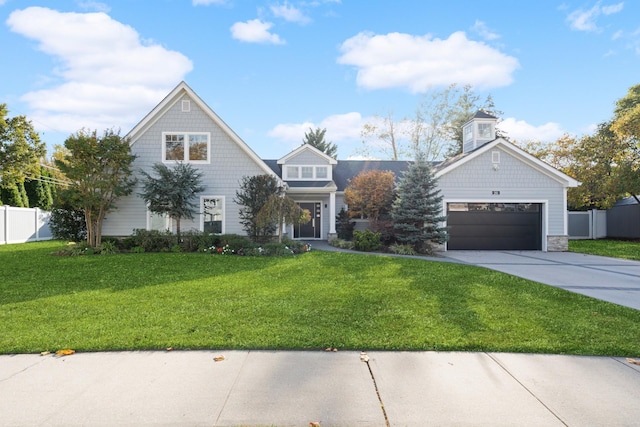 shingle-style home with a garage, a front yard, driveway, and fence