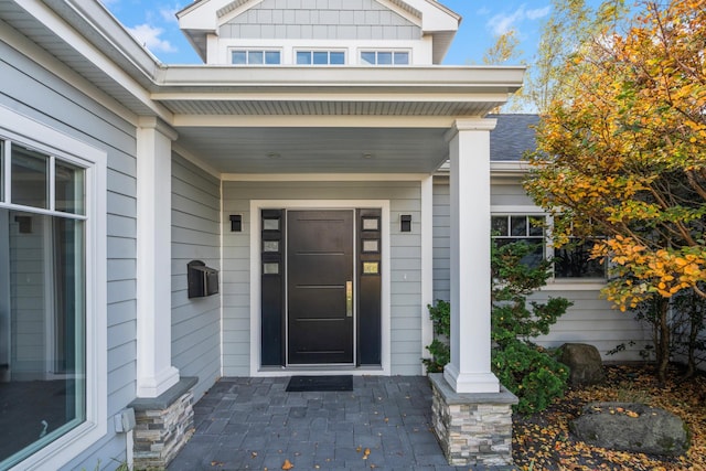 property entrance with covered porch and roof with shingles