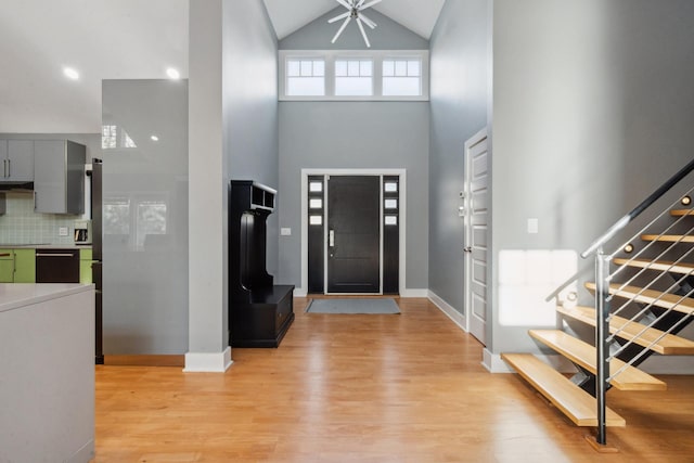 entrance foyer featuring light wood-type flooring, baseboards, stairway, and a high ceiling