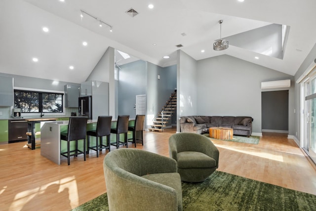 living area featuring high vaulted ceiling, light wood-style flooring, visible vents, stairs, and a wall mounted air conditioner