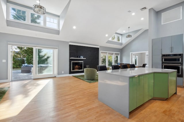 kitchen with a fireplace, visible vents, a center island, multiple ovens, and green cabinetry