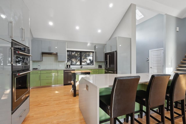 kitchen with dishwasher, light wood-style flooring, decorative backsplash, and high end black refrigerator