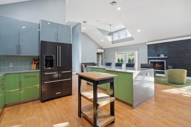 kitchen featuring a warm lit fireplace, high end black fridge, visible vents, light wood-style floors, and open floor plan