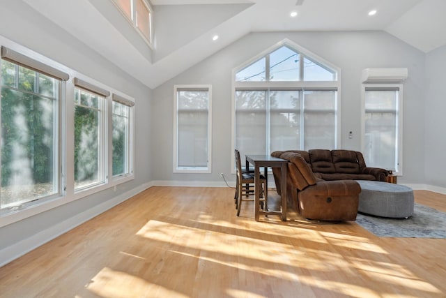 living room with a wall mounted AC, wood finished floors, a wealth of natural light, and baseboards