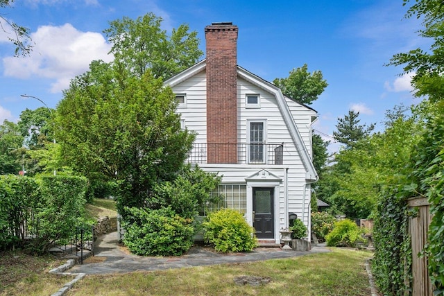 2711 Edgehill Ave, Bronx, NY 10463 - view of side of home with a gambrel roof, a chimney, a balcony, and a lawn