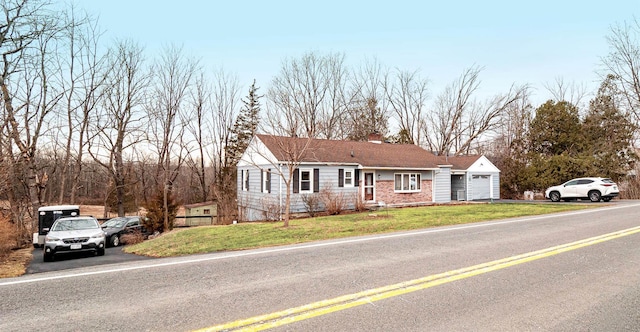 view of front facade featuring driveway, an attached garage, a chimney, and a front lawn