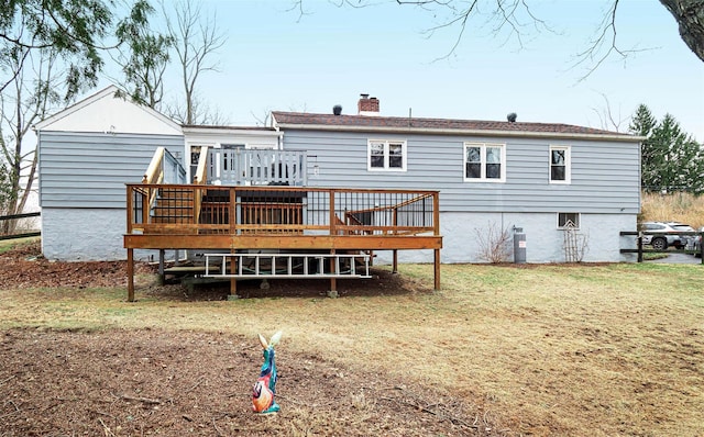 back of property featuring a chimney, a deck, and a yard