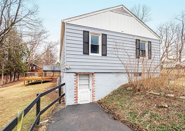 view of property exterior featuring fence, a deck, board and batten siding, and a yard