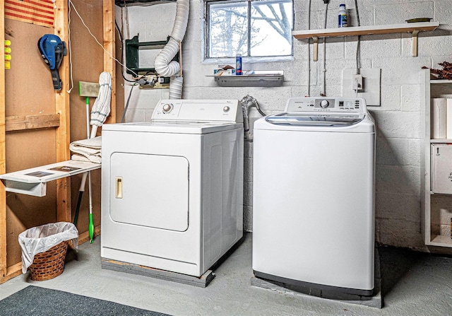 laundry area with concrete block wall, laundry area, and washing machine and dryer