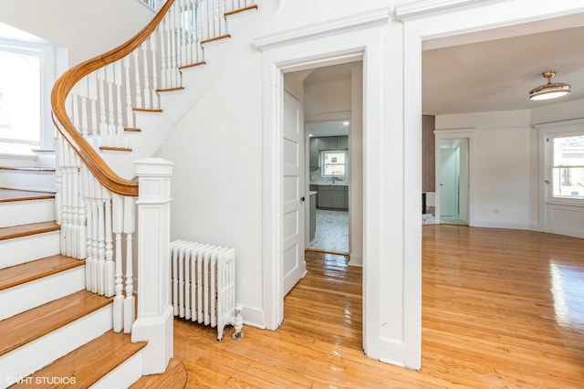 stairs with baseboards, radiator heating unit, and wood finished floors