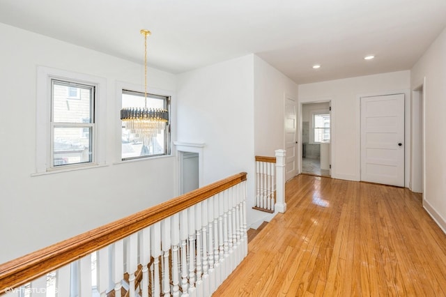 hallway featuring a notable chandelier, recessed lighting, light wood-style floors, an upstairs landing, and baseboards