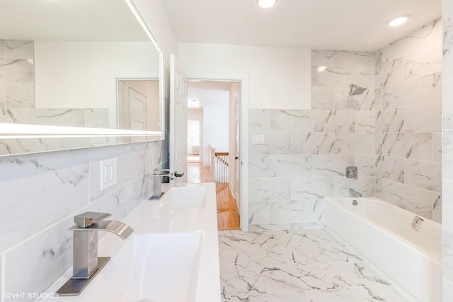 full bath featuring recessed lighting, a sink, tile walls, marble finish floor, and tub / shower combination