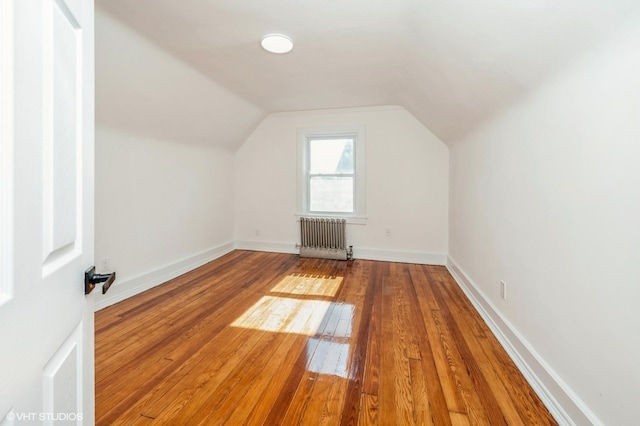 bonus room featuring lofted ceiling, radiator heating unit, baseboards, and hardwood / wood-style floors