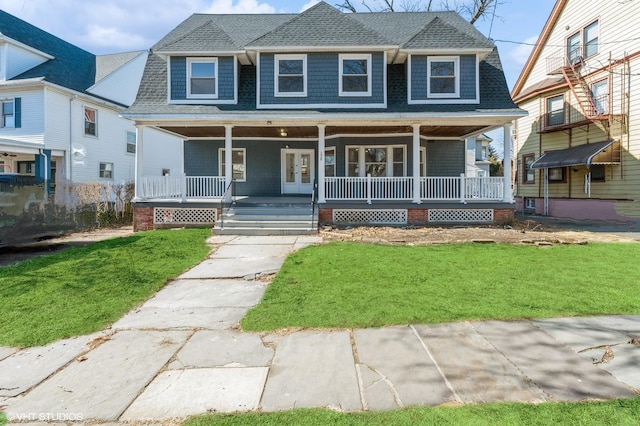 view of front facade with covered porch, roof with shingles, and a front yard