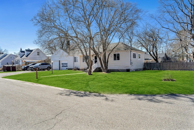 view of front facade with an attached garage, fence, a residential view, and a front yard