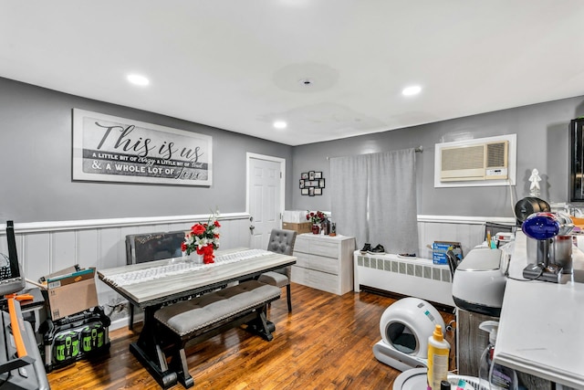 bedroom featuring radiator, wainscoting, a wall mounted air conditioner, and wood finished floors