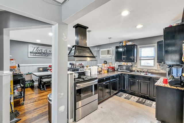 kitchen with island range hood, a sink, stainless steel range with electric stovetop, backsplash, and a wall mounted AC