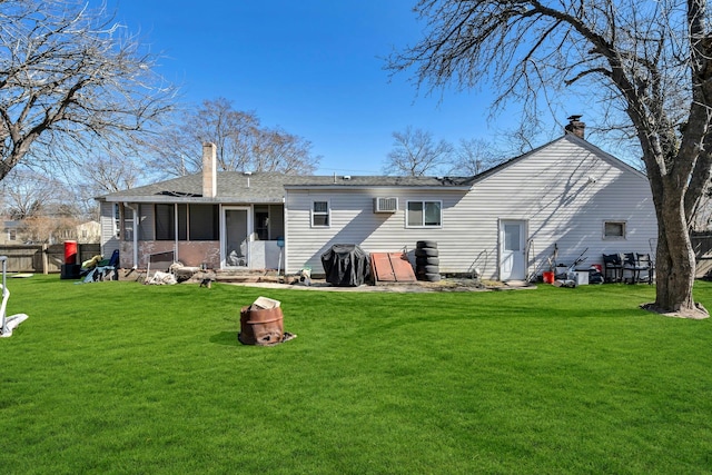 rear view of house with a sunroom, a chimney, and a yard