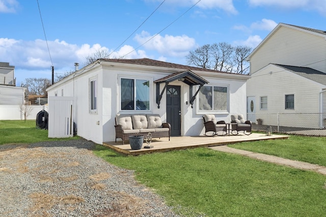 rear view of house with stucco siding, outdoor lounge area, fence, and a lawn