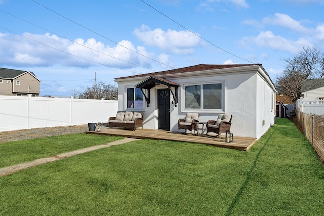 back of house featuring stucco siding, a lawn, a deck, a fenced backyard, and an outdoor living space