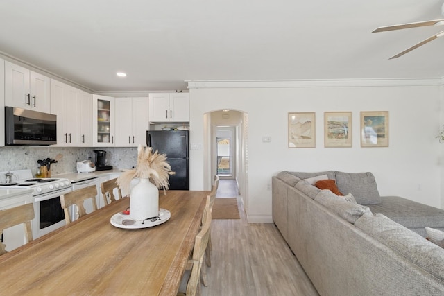 kitchen with arched walkways, white range with electric cooktop, stainless steel microwave, freestanding refrigerator, and open floor plan