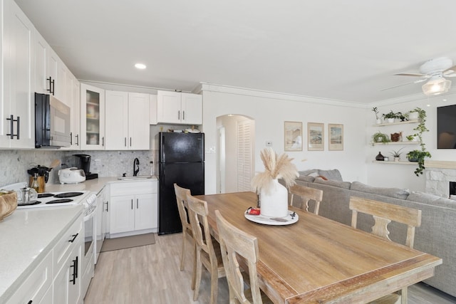 kitchen featuring arched walkways, white range with electric cooktop, decorative backsplash, glass insert cabinets, and freestanding refrigerator