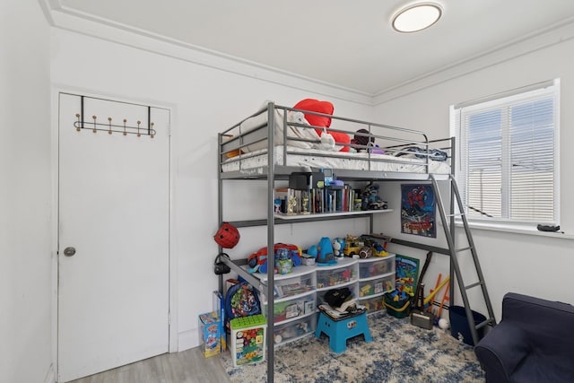 bedroom with crown molding and wood finished floors