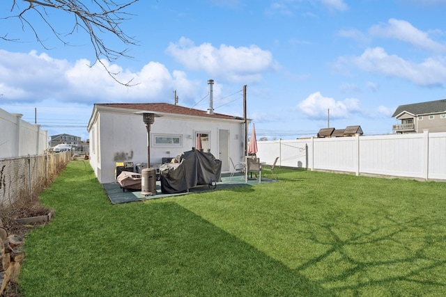 rear view of house with a fenced backyard, a patio, a lawn, and stucco siding