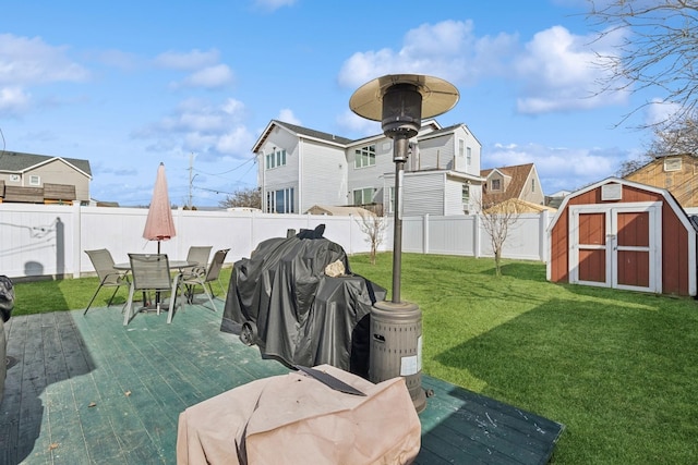 view of yard featuring an outbuilding, a storage unit, outdoor dining space, and a fenced backyard