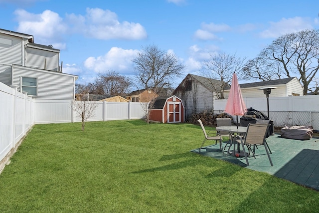 view of yard featuring a storage shed, a fenced backyard, and an outdoor structure