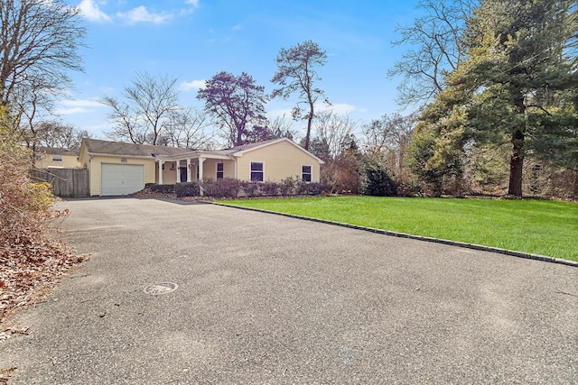 ranch-style house with a front lawn, driveway, an attached garage, and fence