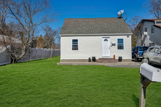 view of front of home featuring a front yard, roof with shingles, and fence