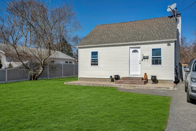 rear view of property featuring a shingled roof, fence, a chimney, and a lawn