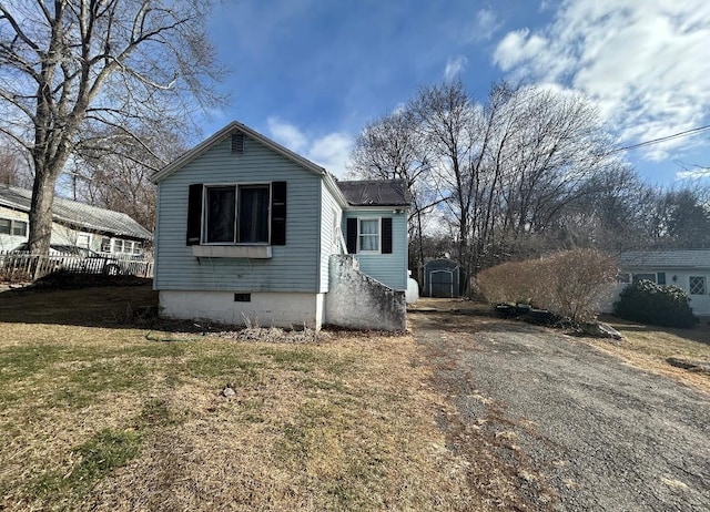 bungalow with crawl space, driveway, a front lawn, and a shed