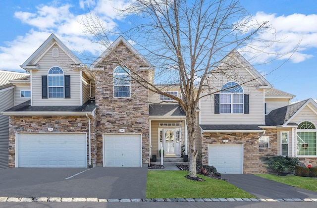 view of front of home featuring driveway, a shingled roof, an attached garage, and a front yard