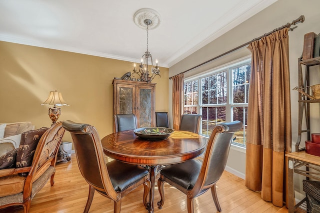 dining room with a notable chandelier, crown molding, baseboards, and light wood-style floors