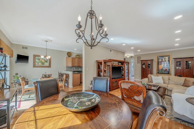 living area with recessed lighting, visible vents, light wood-type flooring, an inviting chandelier, and crown molding