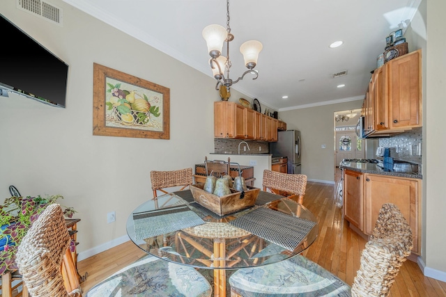 dining space with a notable chandelier, visible vents, ornamental molding, light wood-type flooring, and baseboards