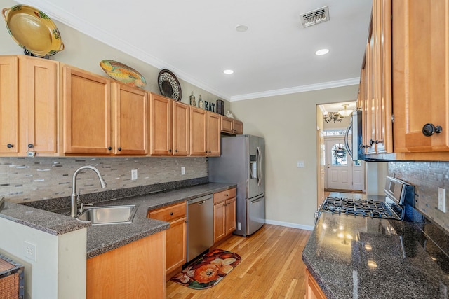 kitchen featuring stainless steel appliances, a sink, visible vents, light wood-style floors, and ornamental molding