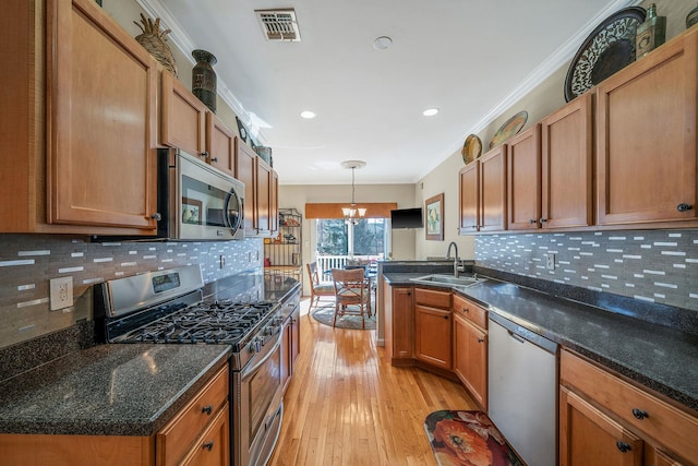 kitchen with visible vents, ornamental molding, stainless steel appliances, a chandelier, and a sink