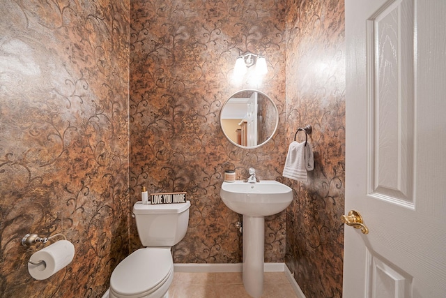 bathroom with baseboards, toilet, and tile patterned floors