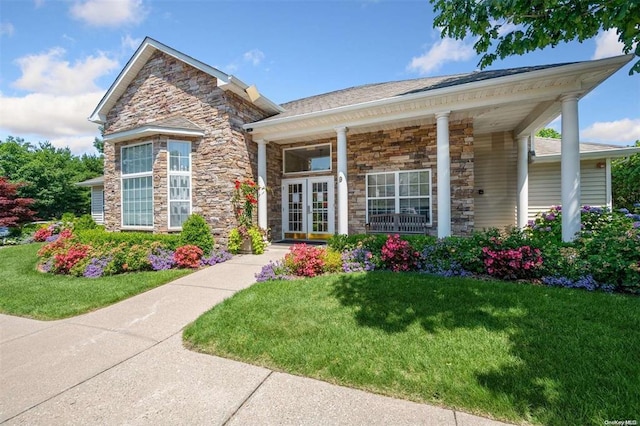 view of front of house featuring stone siding, a front yard, and french doors