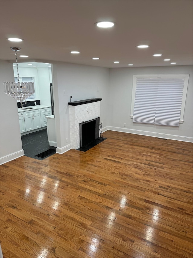 unfurnished living room with a fireplace, a sink, dark wood finished floors, and recessed lighting