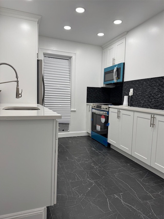 kitchen featuring a sink, stainless steel range with electric cooktop, white cabinets, light countertops, and fridge