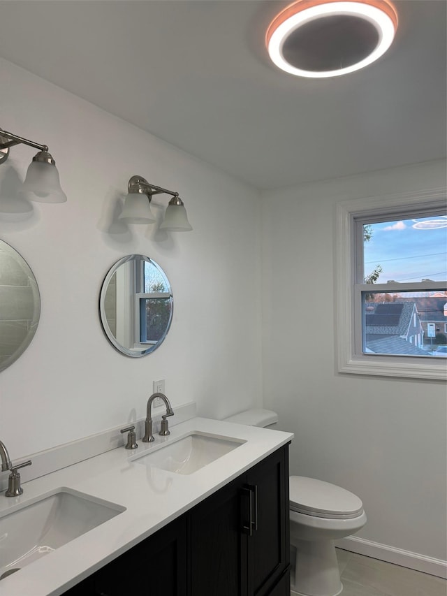 full bathroom with double vanity, a sink, and toilet